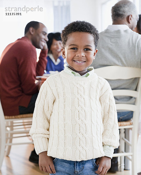 Afroamerikanischer Junge lächelt mit Familie im Hintergrund