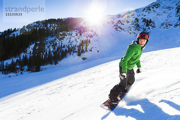 Gemischtrassiger Teenager beim Snowboarden