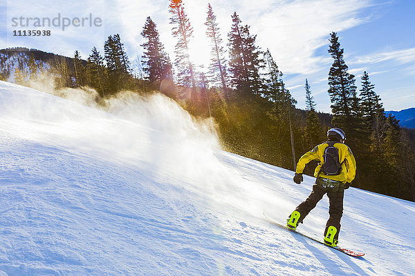 Kaukasischer Teenager beim Snowboarden