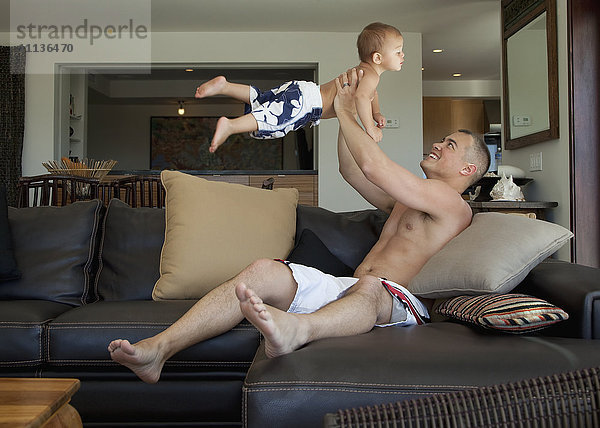 Vater hebt Sohn im Wohnzimmer hoch