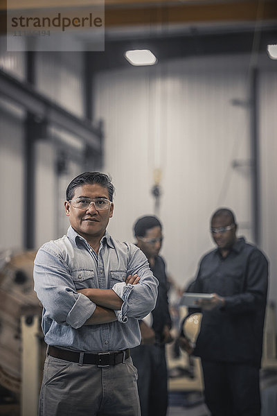 Asiatischer Arbeiter in einer Fabrik stehend