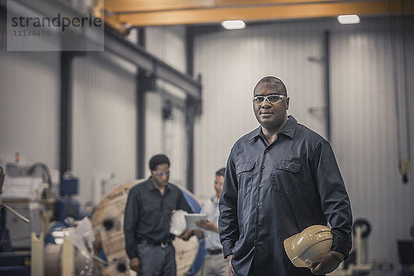 Afroamerikanischer Arbeiter in einer Fabrik stehend