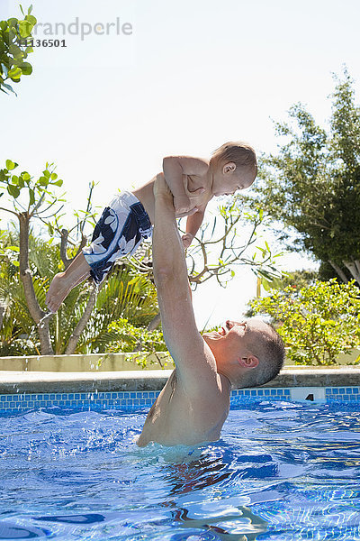 Vater hebt Sohn im Schwimmbad hoch