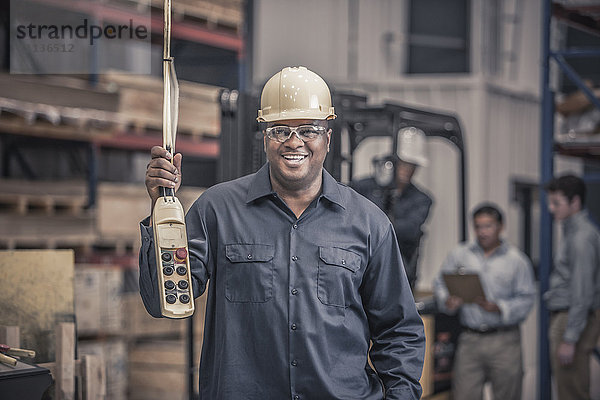 Afroamerikanischer Arbeiter hält Bedienfeld in Fabrik