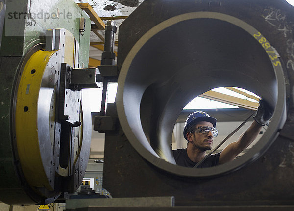Kaukasischer Arbeiter bei der Arbeit an einem Stahlrohr in einer Fabrik