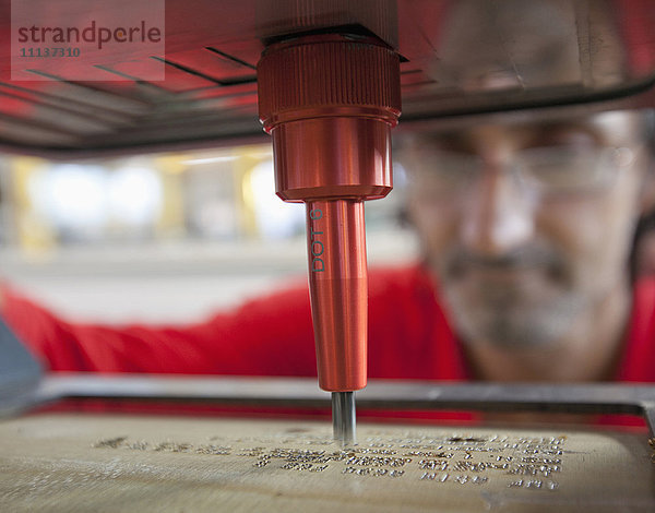 Kaukasischer Arbeiter mit Branding-Maschine in einer Fabrik