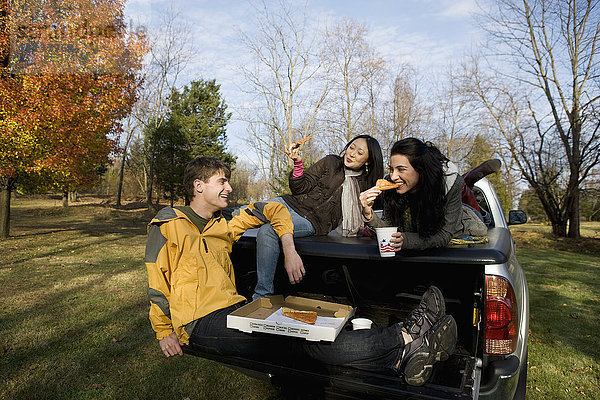 Freunde essen Pizza auf der Ladefläche eines Lastwagens
