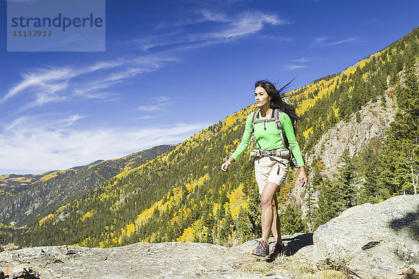 Gemischtrassige Frau beim Wandern auf einer felsigen Bergkuppe