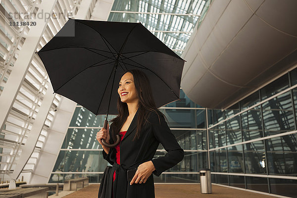 Asiatische Geschäftsfrau unter Regenschirm