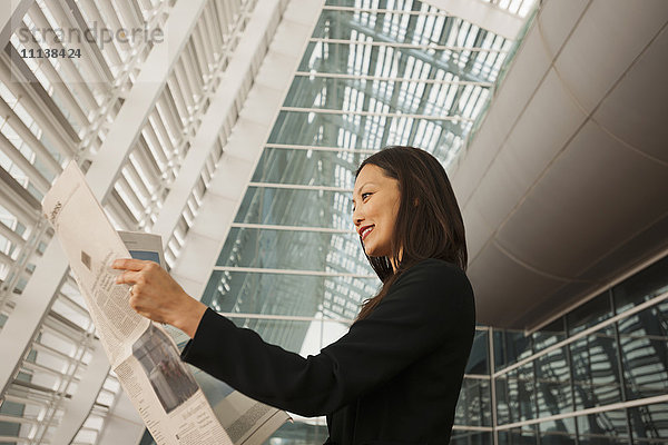 Asiatische Geschäftsfrau liest Zeitung