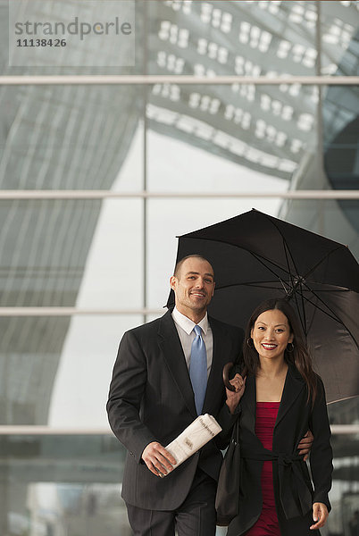 Geschäftsleute stehen mit Regenschirm zusammen