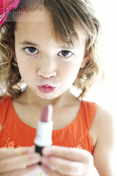 Gemischtrassiges Mädchen spielt mit Lippenstift