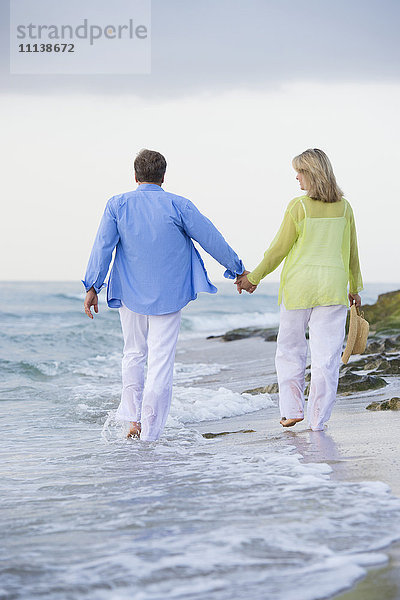 Kaukasisches Paar geht am Strand spazieren