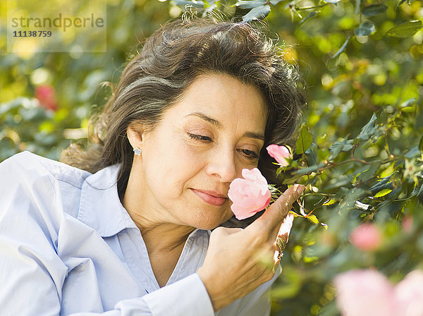 Kaukasische Frau riecht an einer Blume im Freien