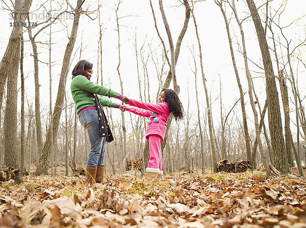 Mutter und Tochter spielen im Herbstlaub