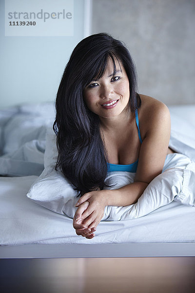Lächelnde Frau im Bett liegend