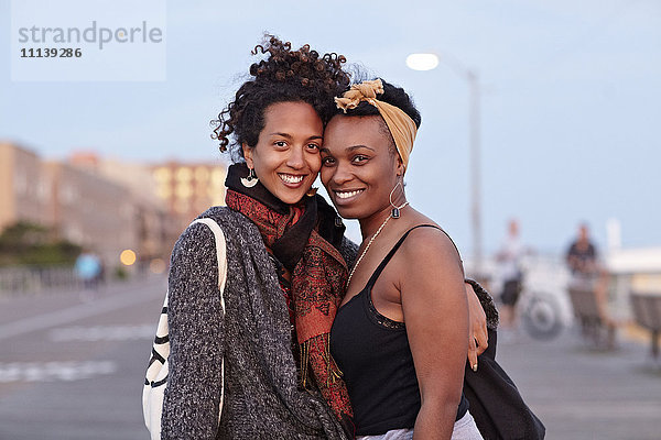 Afroamerikanische Freunde umarmen sich auf dem Bürgersteig