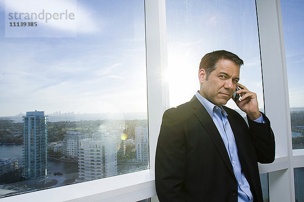 Hispanischer Geschäftsmann  der mit einem Handy telefoniert