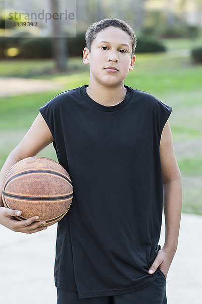 Gemischtrassiger Junge hält Basketball