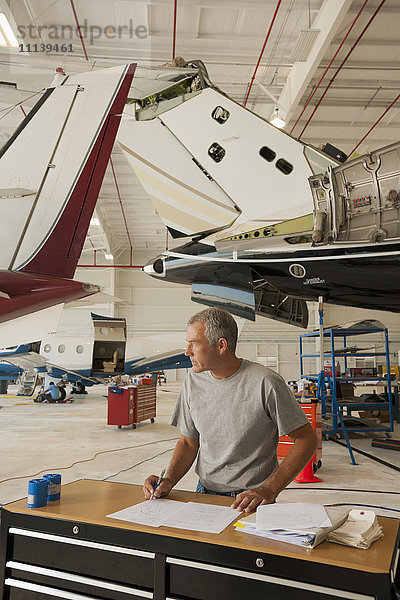 Kaukasischer Mann arbeitet in einem Flugzeughangar