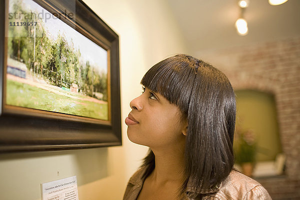 Gemischtrassige Frau bewundert Gemälde in einer Galerie