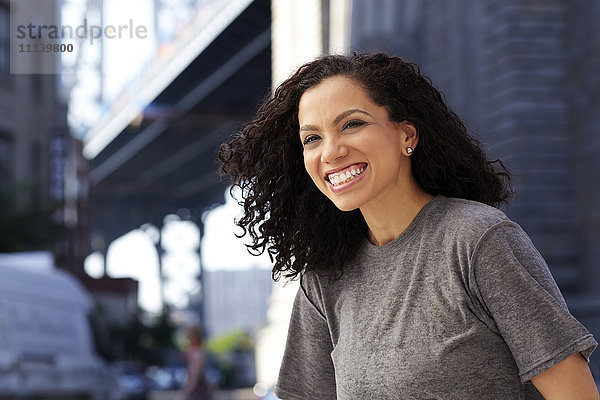 Gemischte Rasse Frau lächelnd unter städtischen Brücke