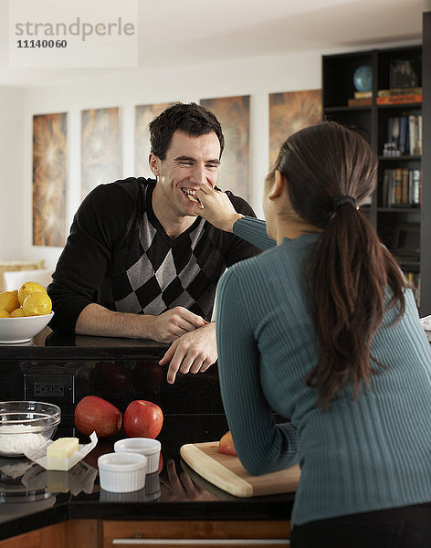 Frau füttert Ehemann in der Küche