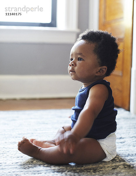 Afroamerikanisches Baby auf dem Boden sitzend