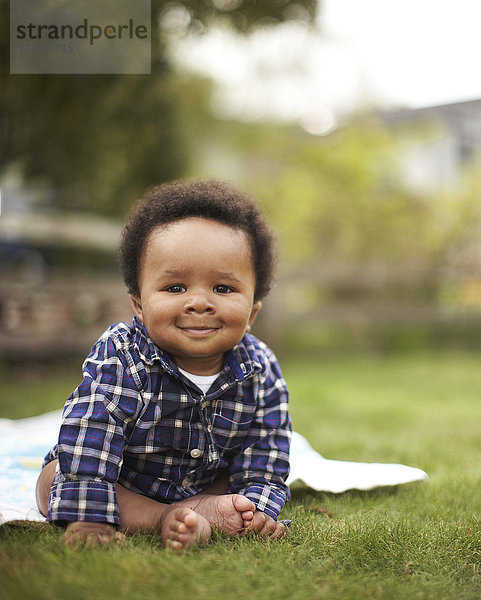 Afroamerikanisches Baby im Gras sitzend