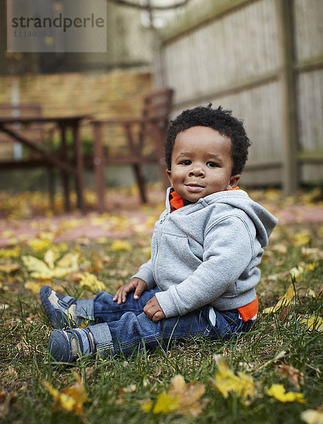 Afroamerikanisches Baby im Gras sitzend