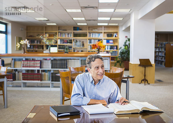 Mann liest in Bibliothek