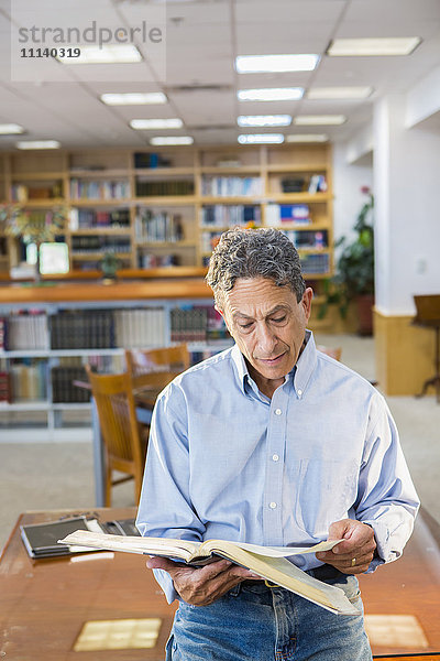 Älterer Mann liest in der Bibliothek
