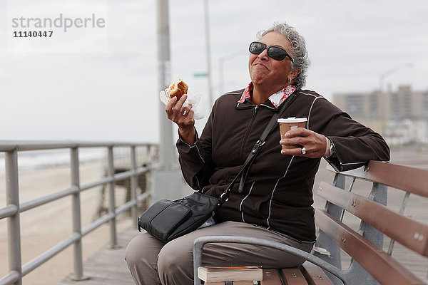 Frauen essen Gebäck und trinken Kaffee an der Strandpromenade