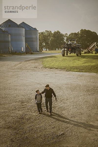 Kaukasischer Vater und Sohn gehen auf einem Bauernhof spazieren