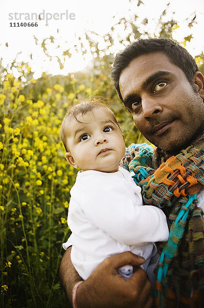 Vater hält Baby im Feld