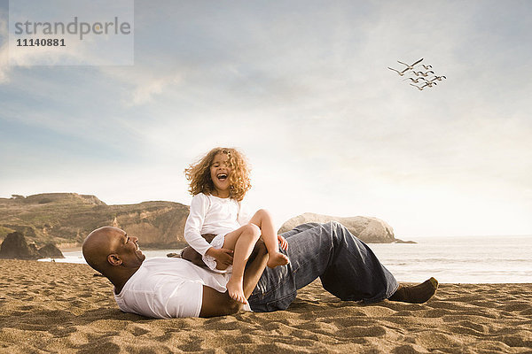 Vater und Tochter lachen am Strand