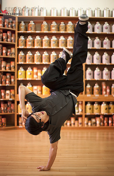 Gemischtrassiger Mann macht Handstand im Laden