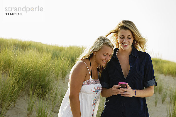Lächelnde Teenager-Mädchen Textnachrichten mit Handy am Strand