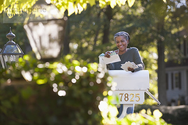 Gemischtrassige Frau liest Post am Briefkasten