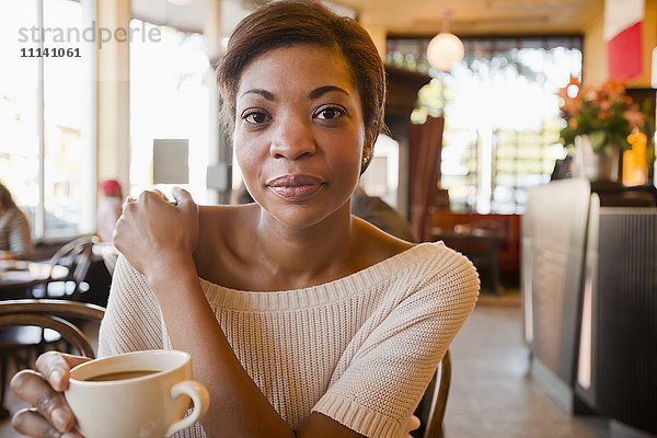 Afroamerikanische Frau trinkt Kaffee in einem Cafe