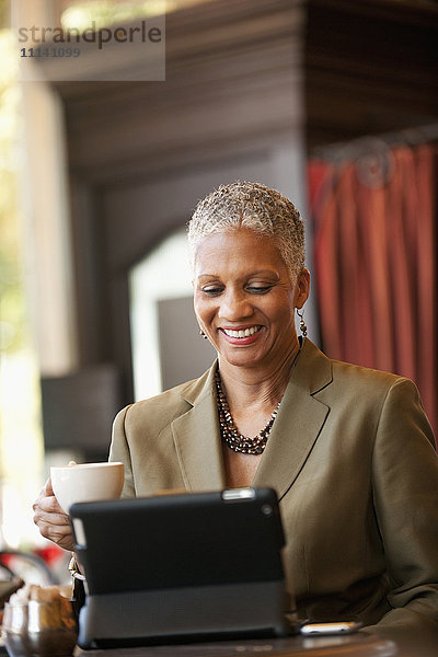 Afroamerikanische Geschäftsfrau benutzt digitales Tablet in einem Café