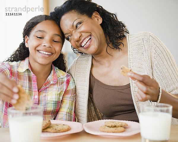 Mutter und Tochter essen gemeinsam Kekse und Milch