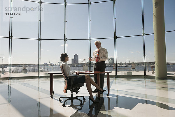 Geschäftsleute arbeiten in einem großen Büro mit Glaswand