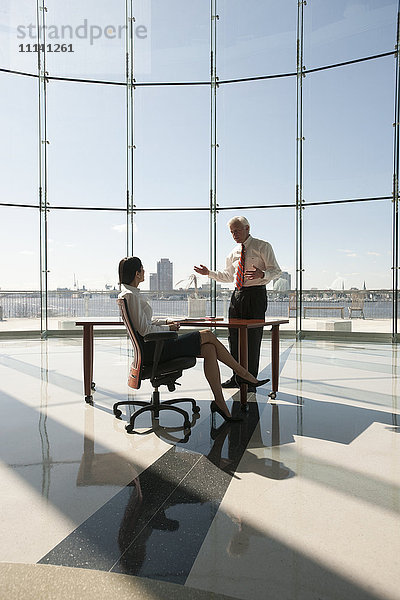 Geschäftsleute arbeiten in einem großen Büro mit Glaswand