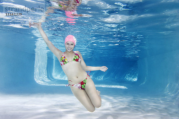 Hispanische Frau im Bikini schwimmt unter Wasser