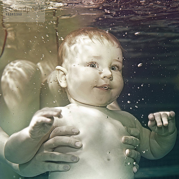 Kaukasisches Baby wird unter Wasser gehalten