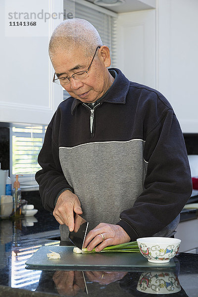 Chinesischer Mann schneidet Zwiebeln in der Küche