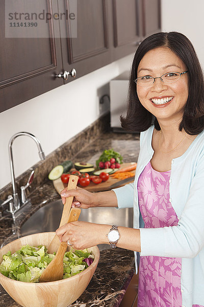Chinesische Frau  die in der Küche einen Salat zubereitet