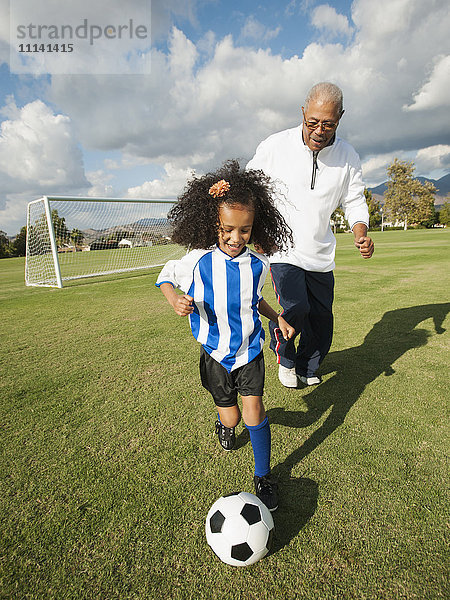 Mann spielt Fußball mit Enkelin