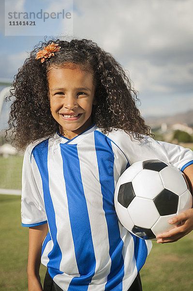 Gemischtrassiges Mädchen hält Fußball